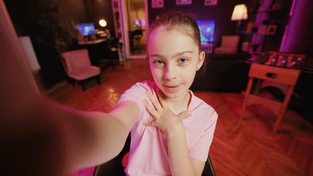 Cute kid teaching her mother how to do viral online videos for social media, filming in POV style. Mom learning how to do trending clips from influencer daughter in home illuminated by pink neon