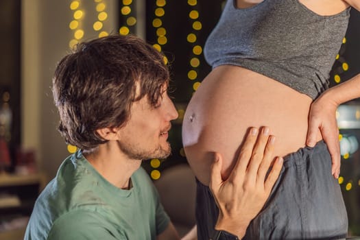 In a tender holiday moment, a husband kisses his wife's pregnant belly, expressing love and anticipation for the Christmas joy to come.