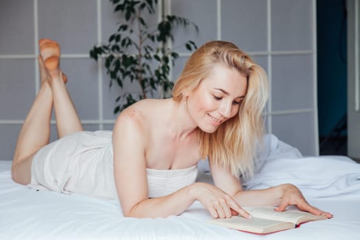 Woman reads a book in the morning in the sleep on the bed