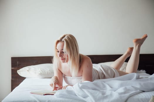 Woman reads a book in the morning in the sleep on the bed