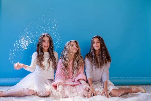 Three fashionable beautiful girls in hats play with snow