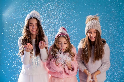 Three fashionable beautiful girls in hats play with snow