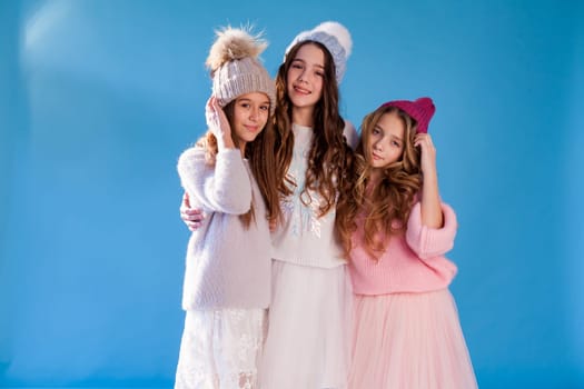three fashionable beautiful girls in winter hats and warm clothes