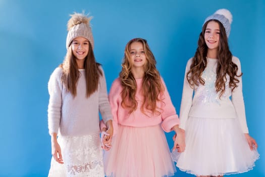 three fashionable beautiful girls in winter hats and warm clothes