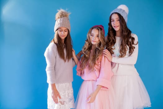 three fashionable beautiful girls in winter hats and warm clothes