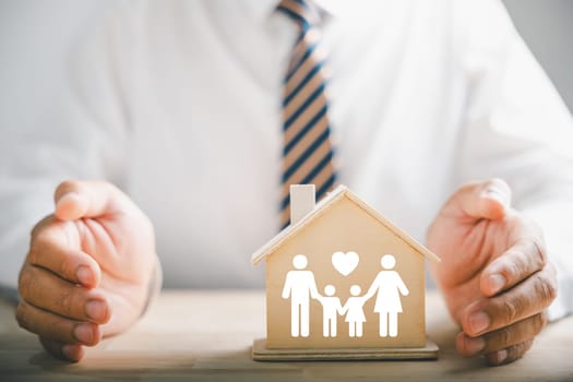 Security and assurance for families depicted. Businessman protective gesture beside family silhouette. Icons for family, life, health, and house insurance. Conveying insurance concept.