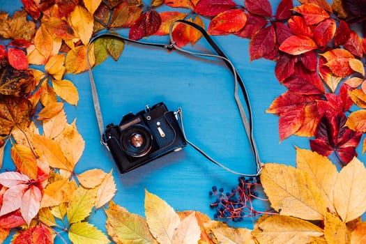 film camera on a wooden background with multicolored leaves