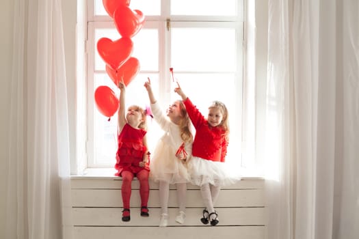 three girls in red and white dresses sitting by the window