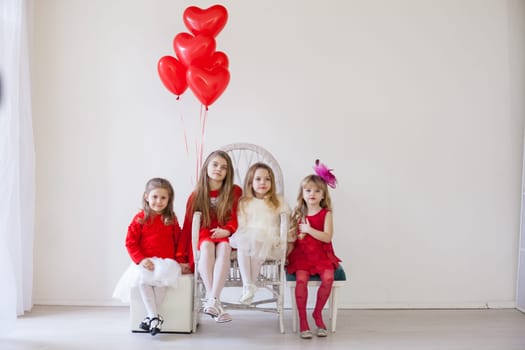 Kids with red balloons for birthday in the interior of the white room