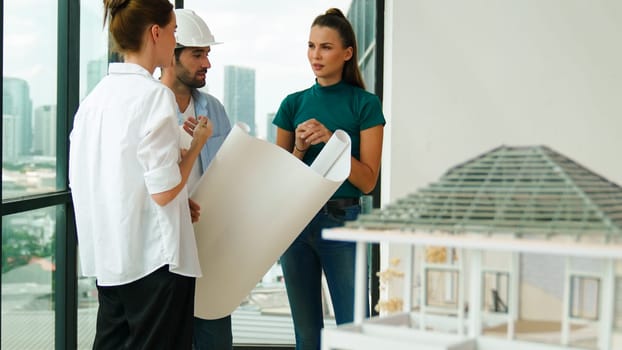 Professional architect engineer team talking, sharing, brainstorming about design while manager hold at project plan. Young architect holding plan while manager listen and point at plan. Tracery