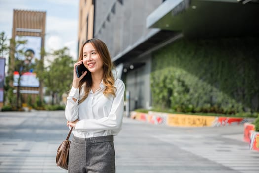 Beautiful young Asian woman calling and talks on telephone or mobile phone in city, Portrait of businesswoman smiling talking on mobile phone, people and technology communication concept