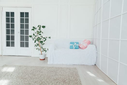 white sofa with a gift in the interior of an empty white room