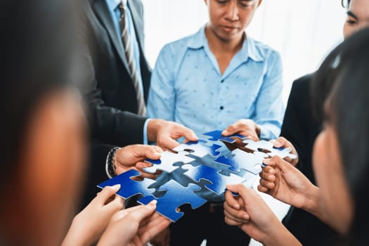 Multiethnic business people holding jigsaw pieces and merge them together as effective solution solving teamwork, shared vision and common goal combining diverse talent. Meticulous