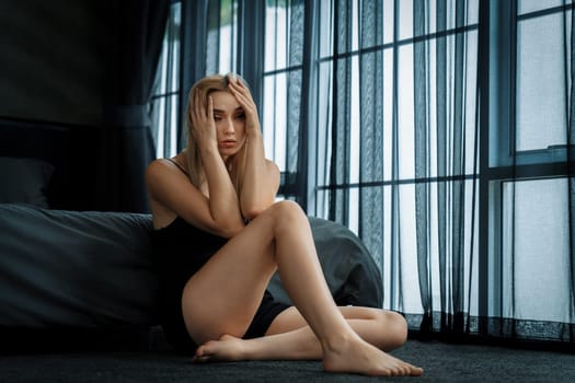 Young woman with critical depression and anxiety disorder from loneliness, mental sickness, or unwanted pregnancy, cuddling herself on dark bedroom. Overwhelming negative thought. Blithe