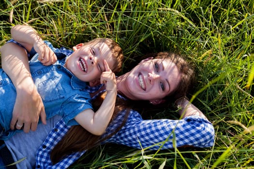 Mom and son lie on the grass in the woods