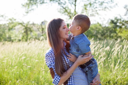 Mom holds a son in her arms in nature