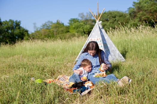 Mom and son eat on a picnic in the woods