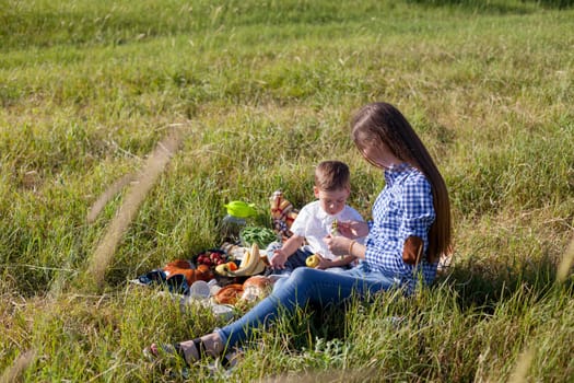 Mom and son eat on a picnic in the woods