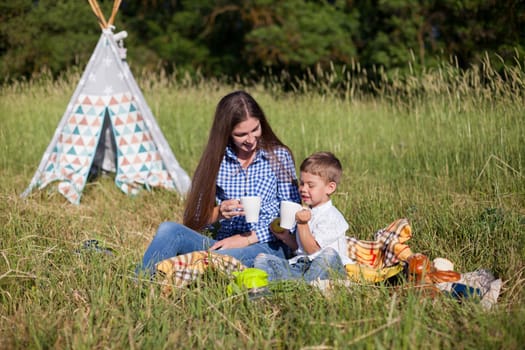 Mom and son eat on a picnic in the woods