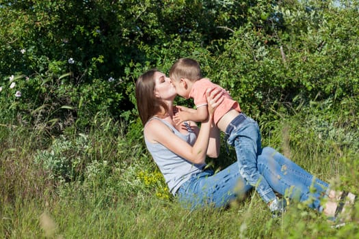 Mom with son playing in the garden on the grass