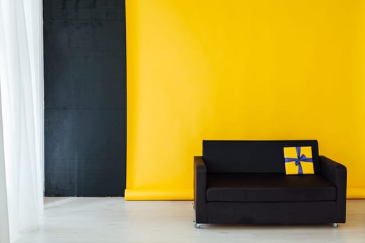 black sofa with gifts in the interior of the room with a yellow background