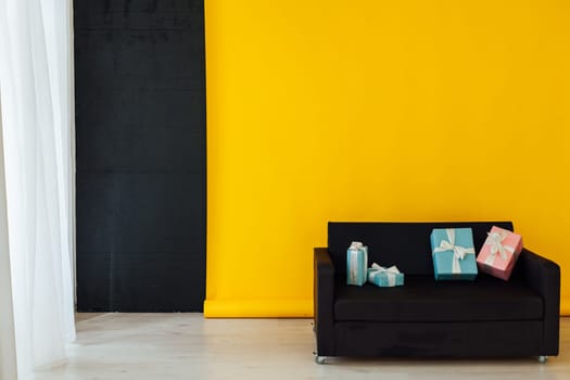 black sofa with gifts in the interior of the room with a yellow background
