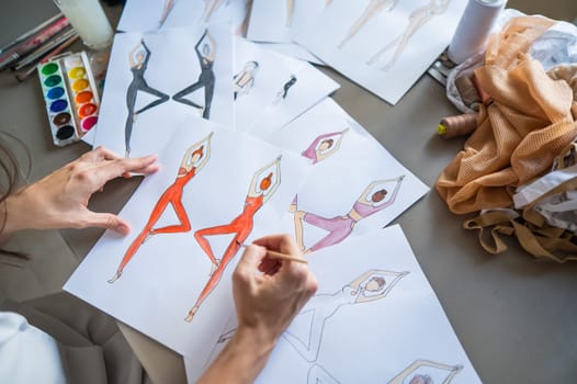 Caucasian woman draws watercolor sketches of sportswear. Close-up of the hands of a fashion designer