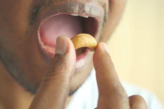 closeup of male mouth eating a cashew nut .