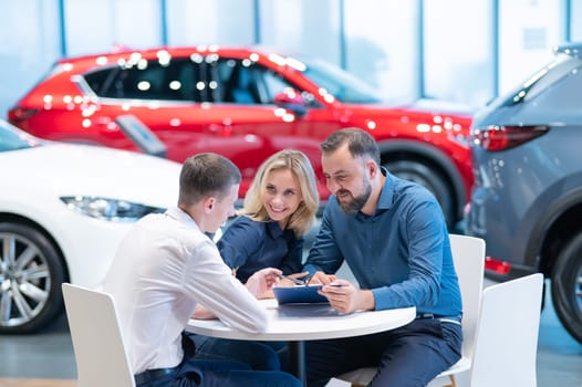 Happy caucasian couple signs a contract for the purchase of a car salon