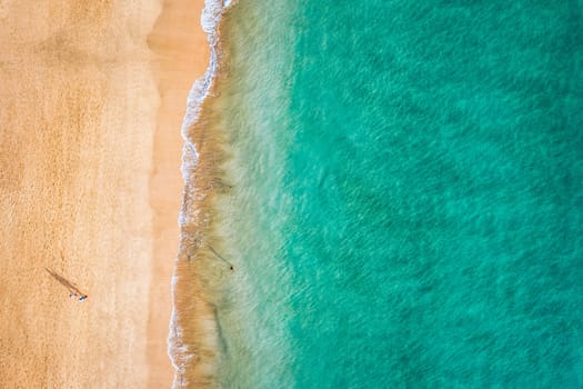 Aerial view of the walking people on the white sandy beach near sea with waves at sunset. Summer holiday. Top view of sporty people, clear azure water. Lifestyle and sport