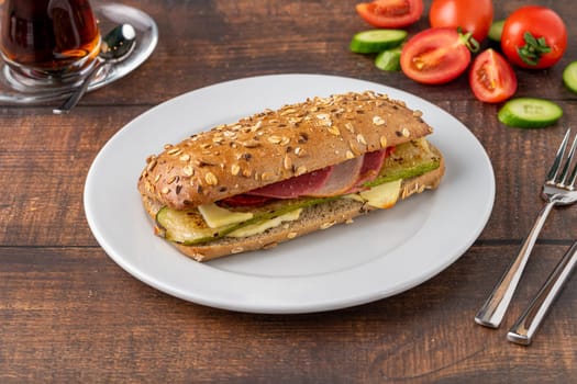 Vegetable and ham sandwich with tea on wooden table