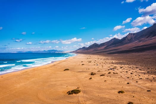 Amazing Cofete beach with endless horizon. Volcanic hills in the background and Atlantic Ocean. Cofete beach, Fuerteventura, Canary Islands, Spain. Playa de Cofete, Fuerteventura, Canary Islands.