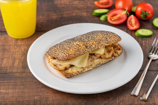 Cheddar cheese and chicken sandwich on white porcelain plate on wooden table