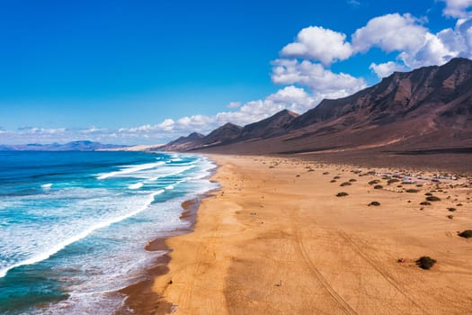 Amazing Cofete beach with endless horizon. Volcanic hills in the background and Atlantic Ocean. Cofete beach, Fuerteventura, Canary Islands, Spain. Playa de Cofete, Fuerteventura, Canary Islands.