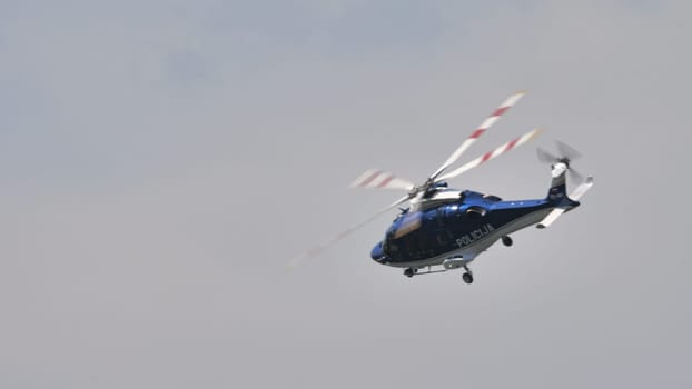 Police helicopter on patrol, with rotor blades in motion, suitable for security and surveillance themes, with copy space.