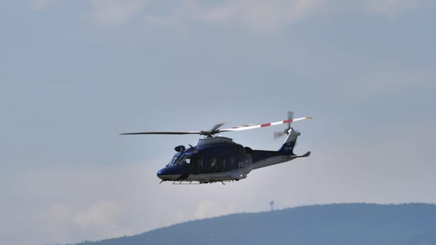 Blue police helicopter flying over a hazy landscape, showcasing law enforcement presence, with copy space.