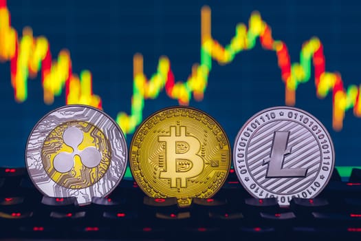 Bitcoin, litecoin and ripple coins currency finance money on graph chart background. Bitcoin as most important cryptocurrency concept. Stack of cryptocurrencies with a golden bitcoin in the middle.