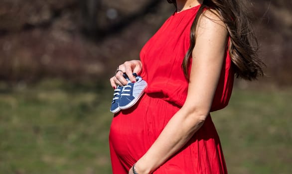Young couple waiting for baby. Expecting parents with little baby boy shoes. Concept of Parents-To-Be. Shoes and sneakers of parents and expected baby. Mom, dad and the future baby Shoes.