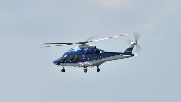 An image capturing the intensity of a police search helicopter in action, with a focus on the fuselage and the cloudy sky.