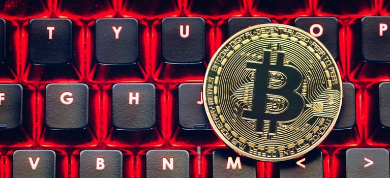 Bitcoin on compuer keyboard in background, symbol of electronic virtual money and mining cryptocurrency concept. Coin crypto currency bitcoin lies on the keyboard. Bitcoin on keyboard.