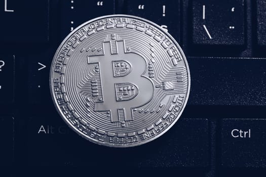 Bitcoin on compuer keyboard in background, symbol of electronic virtual money and mining cryptocurrency concept. Coin crypto currency bitcoin lies on the keyboard. Bitcoin on keyboard.