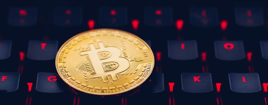 Bitcoin on compuer keyboard in background, symbol of electronic virtual money and mining cryptocurrency concept. Coin crypto currency bitcoin lies on the keyboard. Bitcoin on keyboard.