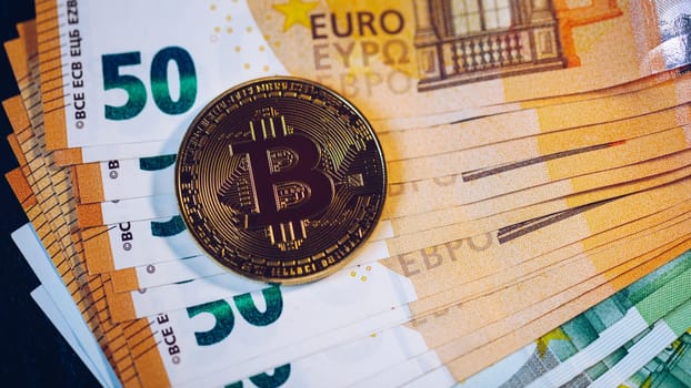 Golden bitcoin over Euro money. Bitcoin cryptocurrency. Crypto currency concept. Bitcoin with euro bills. Bitcoins stacked on euro banknotes.