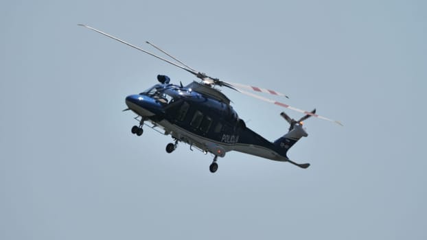 Police helicopter patrolling the area, with clear skies in the background, ideal for editorial use. Includes copyspace.