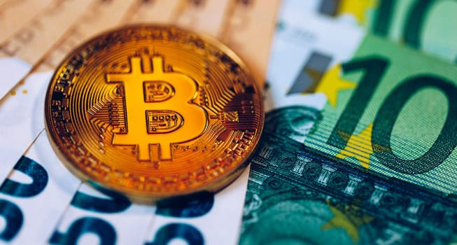 Golden bitcoin over Euro money. Bitcoin cryptocurrency. Crypto currency concept. Bitcoin with euro bills. Bitcoins stacked on euro banknotes.