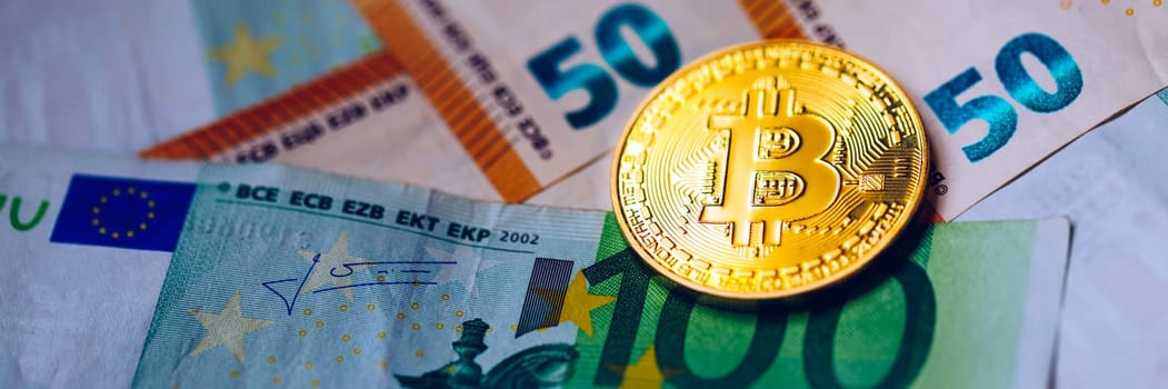 Golden bitcoin over Euro money. Bitcoin cryptocurrency. Crypto currency concept. Bitcoin with euro bills. Bitcoins stacked on euro banknotes.