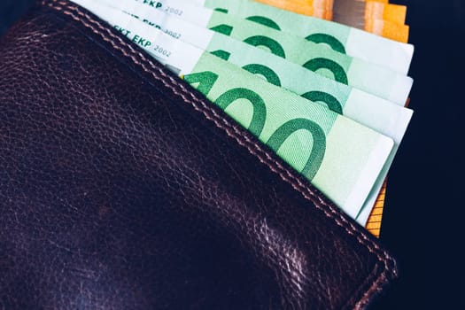Wallet with Euro banknotes. Cash in the wallet on a black background. Euro money in leather wallet.