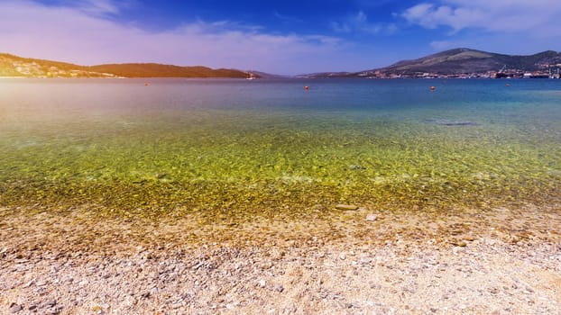 Stones under water. Sea pebbles on the beach. Sea pebbles on the beach sand with transparent water. Natural sea stones closeup. Beach smooth pebbles. Tourism and travel themed. Vacation background. 