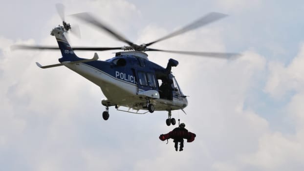 A police helicopter monitors a large crowd during a public event, ensuring safety from above.