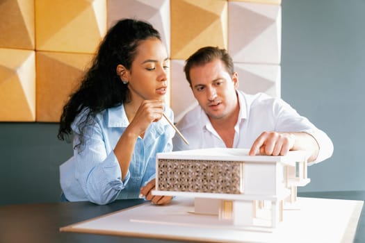 Cooperative skilled architect engineer team discussion about house construction while measuring house model at modern office. Team work, working together and creative design concept. Manipulator.